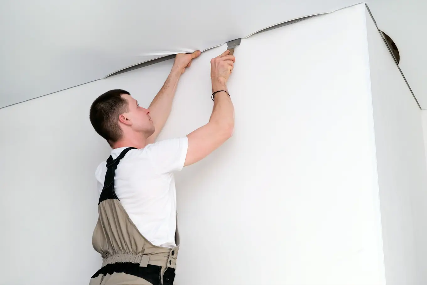 mężczyzna instaluje sufit napinany